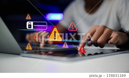 Hand using laptop and tablet with warning triangle alert icons. Concept of cyber security breach, data hacking, computer virus threat, and password identity theft protection. Hand using laptop and tablet with warning triangle alert icons. Concept of cyber security breach, data hacking, computer virus threat, and password identity theft protection. 139831169