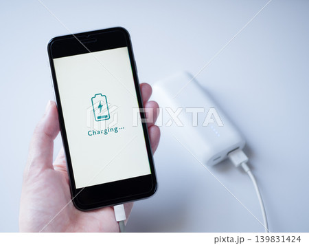 白いモバイルバッテリーで充電中のスマホ(画面デザインはオリジナル制作) 白いモバイルバッテリーで充電中のスマホ(画面デザインはオリジナル制作) 139831424