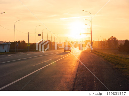 Vehicles travel along a straight highway during a beautiful golden hour Vehicles travel along a straight highway during a beautiful golden hour 139831557