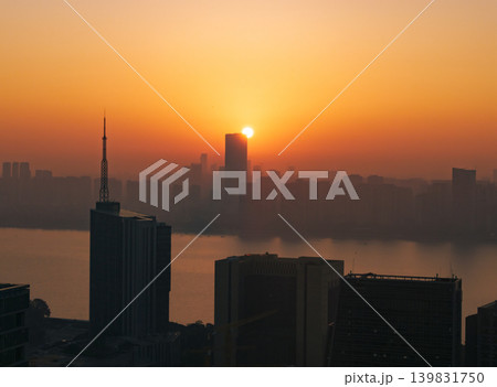 Aerial perspective capturing the sunrise over Hangzhou, China. Silhouetted buildings are visible against the vibrant red and orange sky. City view at dawn with rising sun. 139831750
