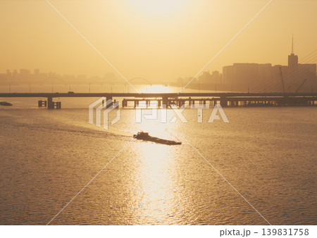 Aerial view of barge travels on Qiantang River under bridges in Hangzhou during golden hour sunset illuminating the water 139831758