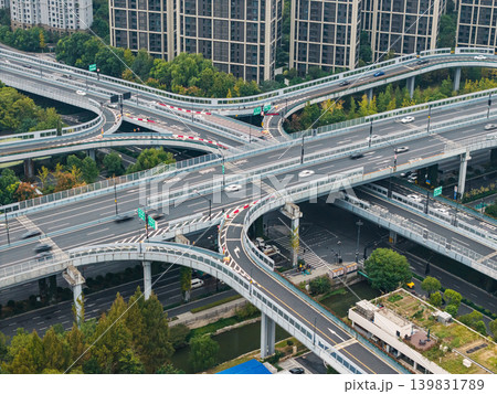 Multilevel highway interchange with numerous vehicles traversing elevated roads and ramps in a dense city environment 139831789