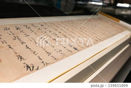 Detailed view of an aged Chinese manuscript, featuring intricate black ink calligraphy on a light brown scroll Detailed view of an aged Chinese manuscript, featuring intricate black ink calligraphy on a light brown scroll 139831809