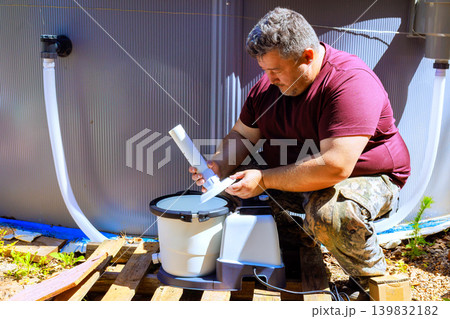 Worker works fixes cleaning pool filter pump water tank near swimming pool on sunny day. 139832182