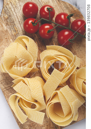 raw pappardelle pasta, on a wooden chopping board, with cherry tomatoes, top view, no people, 139832708