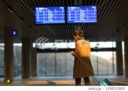Modern Woman Checking Train Schedule on Phone at Station Modern Woman Checking Train Schedule on Phone at Station 139832900