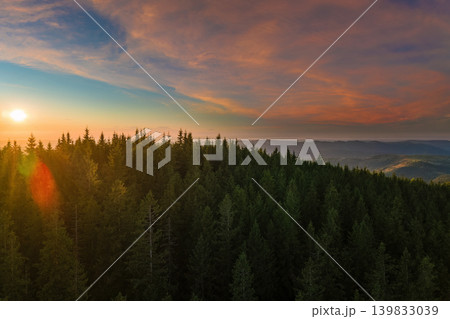 Aerial view of amazing mountain landscape. Bright colorful sunset in wild national park highlands. Dark spruce woods illuminated with yellow setting sun Aerial view of amazing mountain landscape. Bright colorful sunset in wild national park highlands. Dark spruce woods illuminated with yellow setting sun 139833039