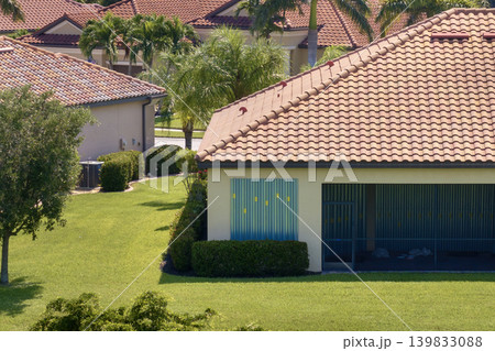 Steel sheets mounted as storm shutters for hurricane protection of house windows. Protective measures before natural disaster in Florida Steel sheets mounted as storm shutters for hurricane protection of house windows. Protective measures before natural disaster in Florida 139833088