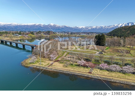岩手県御所湖周辺の桜並木と残雪の山々を望む空撮写真 139833256