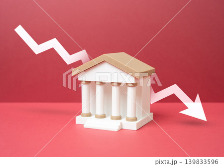 A bank and a downward arrow. Losses in the banking sector. Bank downsizing and branch closures caused by economic pressure and declining profitability. A bank and a downward arrow. Losses in the banking sector. Bank downsizing and branch closures caused by economic pressure and declining profitability. 139833596