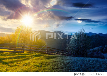 day meet night in mountainous rural landscape in spring. epic view of valley fields at twilight. sun and moon over alpine meadow. carpathian mountains countryside with forest near pasture. harmony 139833725