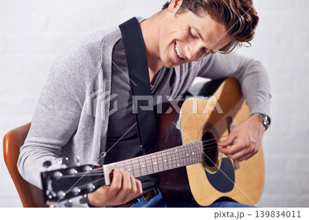 Music, smile and happy man with guitar for artistic, sounds or creative expression on wall background. Musical, instrument and male person with acoustic, melody or feel good hobby, fun or practice Music, smile and happy man with guitar for artistic, sounds or creative expression on wall background. Musical, instrument and male person with acoustic, melody or feel good hobby, fun or practice 139834011