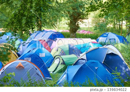 Camping, tents and outdoor music festival in park on holiday or vacation in summer forest. Camp, site and shelter setup at party, event or travel in woods for concert, adventure and crowded carnival Camping, tents and outdoor music festival in park on holiday or vacation in summer forest. Camp, site and shelter setup at party, event or travel in woods for concert, adventure and crowded carnival 139834022
