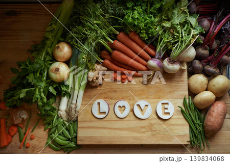 Food, chopping board and message for love, nutrition and cooking for wellbeing or eating. Home, above and vegetables for diet, health and vitamins in kitchen for vegan, vitality and top view Food, chopping board and message for love, nutrition and cooking for wellbeing or eating. Home, above and vegetables for diet, health and vitamins in kitchen for vegan, vitality and top view 139834068