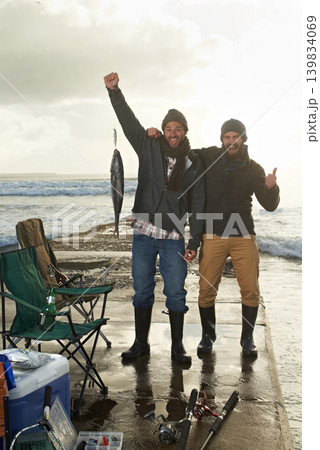 Happy, portrait and men fishing at beach with pride for tuna catch on ocean pier at sunset. Fisherman, friends and smile holding fish in hand in nature at sea on holiday, adventure or vacation Happy, portrait and men fishing at beach with pride for tuna catch on ocean pier at sunset. Fisherman, friends and smile holding fish in hand in nature at sea on holiday, adventure or vacation 139834069