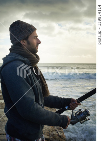 Fishing, relax and travel with man at beach for adventure, holiday and hobby break. Sunset, calm and patience with male fisherman and casting rod pole in nature for recreation, view and vacation Fishing, relax and travel with man at beach for adventure, holiday and hobby break. Sunset, calm and patience with male fisherman and casting rod pole in nature for recreation, view and vacation 139834114