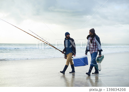 Hobby, fishing and men walking on beach together with cooler, tackle box and holiday conversation. Ocean, fisherman and friends with rods, bait and tools at waves on winter morning vacation at sea. Hobby, fishing and men walking on beach together with cooler, tackle box and holiday conversation. Ocean, fisherman and friends with rods, bait and tools at waves on winter morning vacation at sea. 139834208