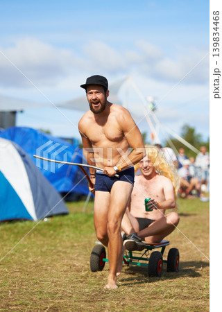 People, outdoor and alcohol at music festival with wagon for fun social party, game and camp. Crazy, friends and person with beer or drink camping at event with freedom on vacation with cart on grass 139834468