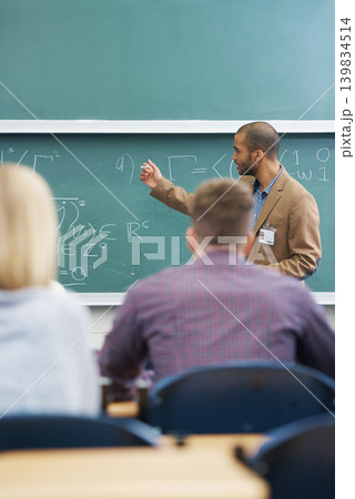 Board, lecture and professor with students in classroom for mathematics lesson at university campus. Education, learning and college teacher explaining work or teaching for assignment, test or exam. Board, lecture and professor with students in classroom for mathematics lesson at university campus. Education, learning and college teacher explaining work or teaching for assignment, test or exam. 139834514