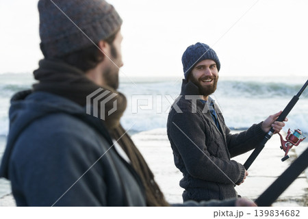 People, fishing and friends at beach for hobby, relaxing and casting a line by ocean with gear. Men, fisherman and together on vacation or holiday, happy and bonding by waves and support on adventure 139834682
