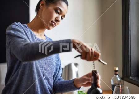 Woman, opening wine and bottle for dinner, evening meal with corkscrew and preparing to drink for enjoyment and nutrition. Alcoholic beverage, tools or equipment with cooking for dining in kitchen Woman, opening wine and bottle for dinner, evening meal with corkscrew and preparing to drink for enjoyment and nutrition. Alcoholic beverage, tools or equipment with cooking for dining in kitchen 139834689