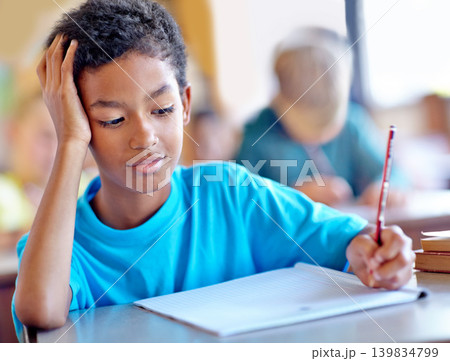 Student, boy and writing notes for studying in classroom, book and problem solving at school. Male person, child and information for exam prep in notebook, solution and journal for assessment or test 139834799