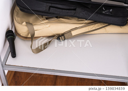 Black microphone and instrument gig bags on a white storage shelf. Music equipment and audio gear background. Black microphone and instrument gig bags on a white storage shelf. Music equipment and audio gear background. 139834839