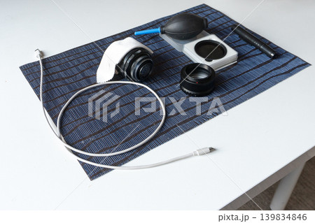 Top view of camera cleaning kit and vintage lens on a striped mat. Flat lay of photography equipment maintenance tools including blower, cloth, and cable. Top view of camera cleaning kit and vintage lens on a striped mat. Flat lay of photography equipment maintenance tools including blower, cloth, and cable. 139834846