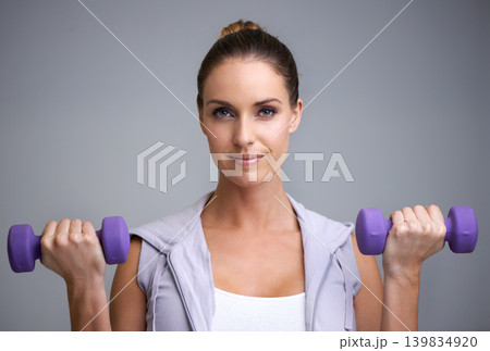 Happy woman, portrait and dumbbells for weightlifting, fitness or exercise on a gray studio background. Face of active, female person or athlete for strength, muscle gain or workout on mockup space Happy woman, portrait and dumbbells for weightlifting, fitness or exercise on a gray studio background. Face of active, female person or athlete for strength, muscle gain or workout on mockup space 139834920