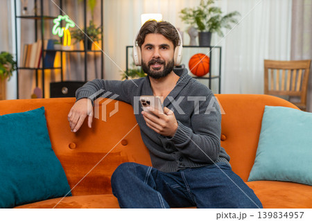 Indian man with wireless headphones listens playlist dances positive mood chill music session vibe Indian man with wireless headphones listens playlist dances positive mood chill music session vibe 139834957