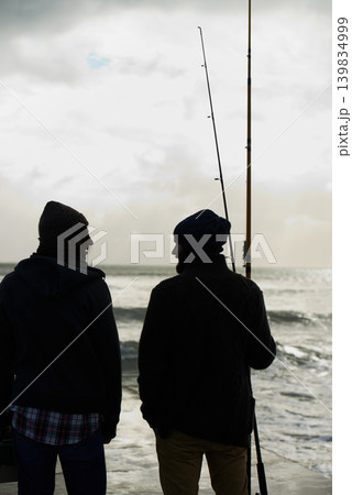 Fishing, fisherman and men by ocean talking with rod, reel and equipment to catch fish for hobby. Friends, sports and people cast line for adventure on holiday, vacation or weekend together in nature Fishing, fisherman and men by ocean talking with rod, reel and equipment to catch fish for hobby. Friends, sports and people cast line for adventure on holiday, vacation or weekend together in nature 139834999