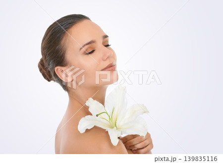Cosmetics, flower and beautiful woman in studio with glamour, glow and makeup face routine. Beauty, confident and young female person with floral plant for facial cosmetology by white background. Cosmetics, flower and beautiful woman in studio with glamour, glow and makeup face routine. Beauty, confident and young female person with floral plant for facial cosmetology by white background. 139835116