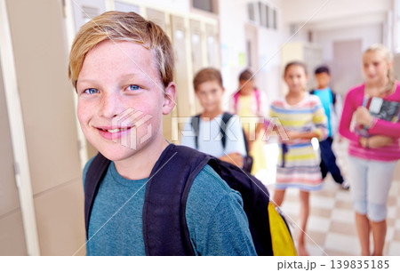 Student, portrait and kid with smile in hallway with education, study and backpack for back to school. Youth, young boy and learning with friends on campus with children and happy in a corridor 139835185
