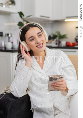 Young woman in wireless headphones listens to music with smartphone relax closed eyes chill zen mood Young woman in wireless headphones listens to music with smartphone relax closed eyes chill zen mood 139835475