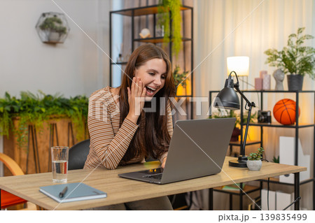 Young woman reads high project score on laptop shouts wow smiles wide and adds thank you review note 139835499