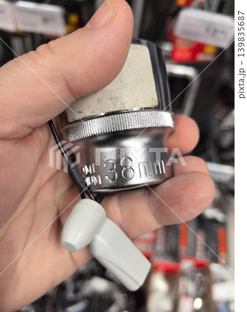 Hand holding a shiny tool with a 38mm label in a hardware store 139835687