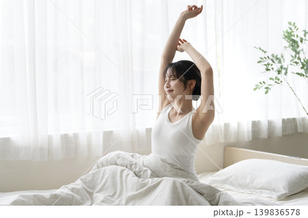 起床してベッドの上で伸びをする若い女性 横顔 起床してベッドの上で伸びをする若い女性 横顔 139836578