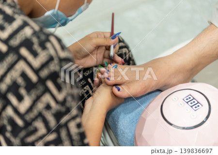 Professional pedicure service colorful nail polish application on toes in beauty salon during foot care treatment Professional pedicure service colorful nail polish application on toes in beauty salon during foot care treatment 139836697