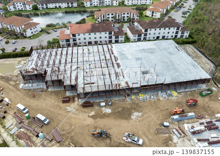 Construction site with hardhat workers assembling metal frame walls. Aerial view of large development area of commercial structure. Real estate market in the USA Construction site with hardhat workers assembling metal frame walls. Aerial view of large development area of commercial structure. Real estate market in the USA 139837155