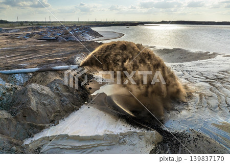 Aerial view of phosphate mining field with pipeline ejecting wet sand and mineral-rich slurry onto settling area. Aerial view of phosphate mining field with pipeline ejecting wet sand and mineral-rich slurry onto settling area. 139837170