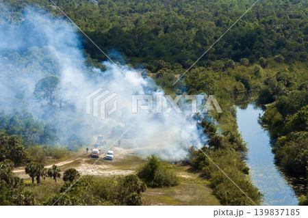 Wild vegetation fire spreads across forested landscape in Florida, with firefighters working in heavy smoke and intense heat to control the flames during dry season 139837185