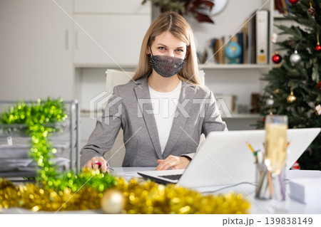 Portrait of young woman office worker in mask in Christmas decorated office 139838149