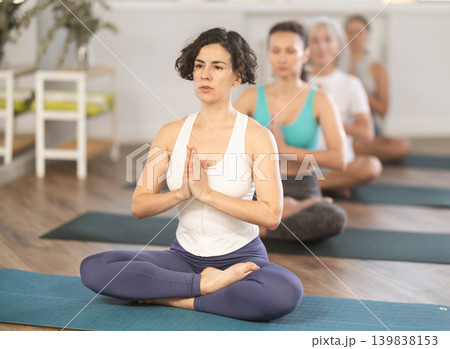 Adult woman doing yoga in group in studio 139838153