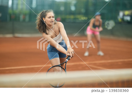 Two young women playing doubles tennis Two young women playing doubles tennis 139838360