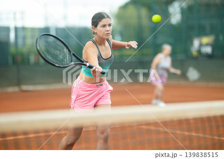 Focused girl playing doubles tennis on outdoor court Focused girl playing doubles tennis on outdoor court 139838515