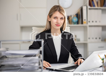 Portrait of young woman office worker sitting at table Portrait of young woman office worker sitting at table 139838604