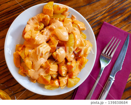 Spanish cuisine patatas bravas served with sauce on plate on wooden table Spanish cuisine patatas bravas served with sauce on plate on wooden table 139838684