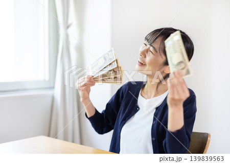 10枚の1万円札を広げて持ち、微笑む日本人の若い女性 10枚の1万円札を広げて持ち、微笑む日本人の若い女性 139839563