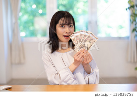 5枚の1万円札を手に微笑む日本人の若い女性 139839758