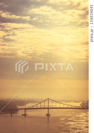 Bridge over the river in golden hour. Dramatic evening sky with cityscape and bridge. Spring Kyiv landmark, Ukraine. Sunrise above Dnipro river. Transportation bridge over the water. Big city in dawn Bridge over the river in golden hour. Dramatic evening sky with cityscape and bridge. Spring Kyiv landmark, Ukraine. Sunrise above Dnipro river. Transportation bridge over the water. Big city in dawn 139839845